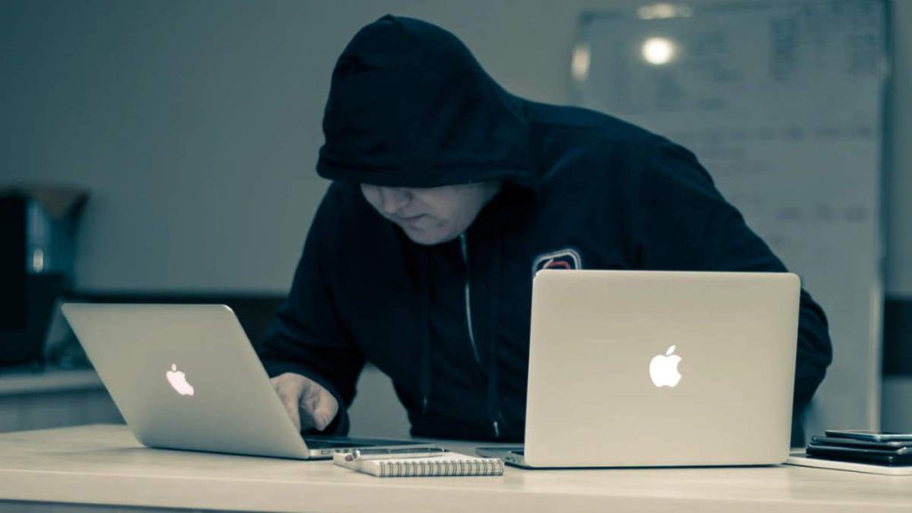I did my own research - A conspiracy therorist, a man in black, is using two laptop computers, searchng Internet for conspiracies