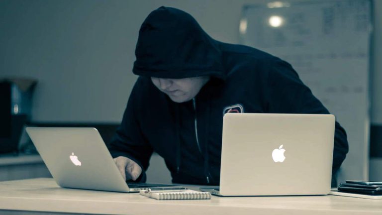 I did my own research - A conspiracy therorist, a man in black, is using two laptop computers, searchng Internet for conspiracies